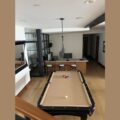 Regulation pool table in a bright room showing its heavy wooden frame